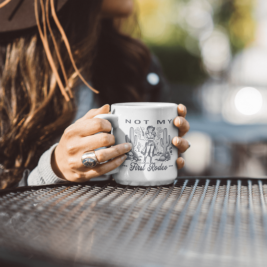 woman holding a 11oz white ceramic mug that says not my first rodeo